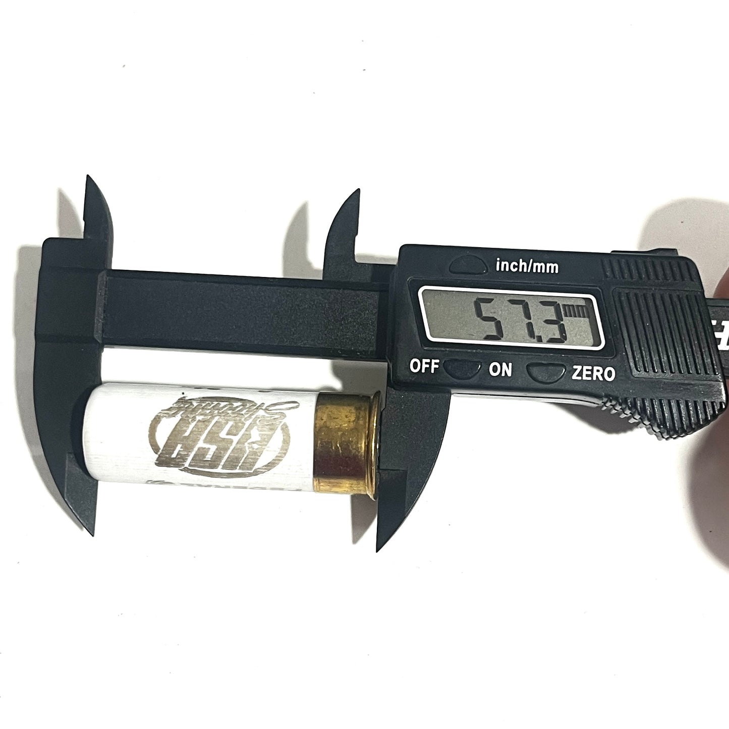 A white once-fired shell with USA Shooting text being measured for diameter with a black digital caliper reading 57.3.