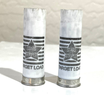 Two white 12 gauge empty shotgun shells printed Stars and Stripes Target Load with silver bases standing on a tile surface