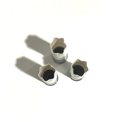 3 white shotgun shell hulls with silver bases, viewed from above showing black powder residue inside the open mouths