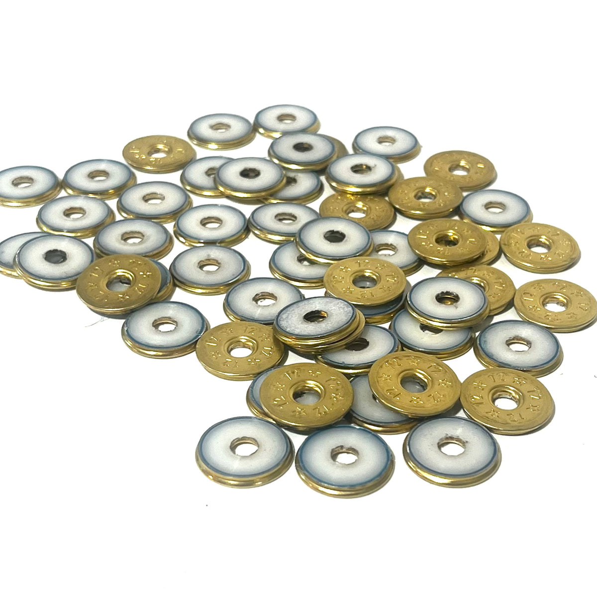 A pile of deprimed 12 gauge shotgun shell slices showing white plastic wad centers ringed in brass