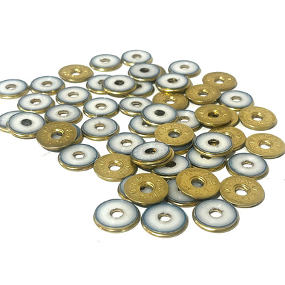 A pile of deprimed 12 gauge shotgun shell slices showing white plastic wad centers ringed in brass