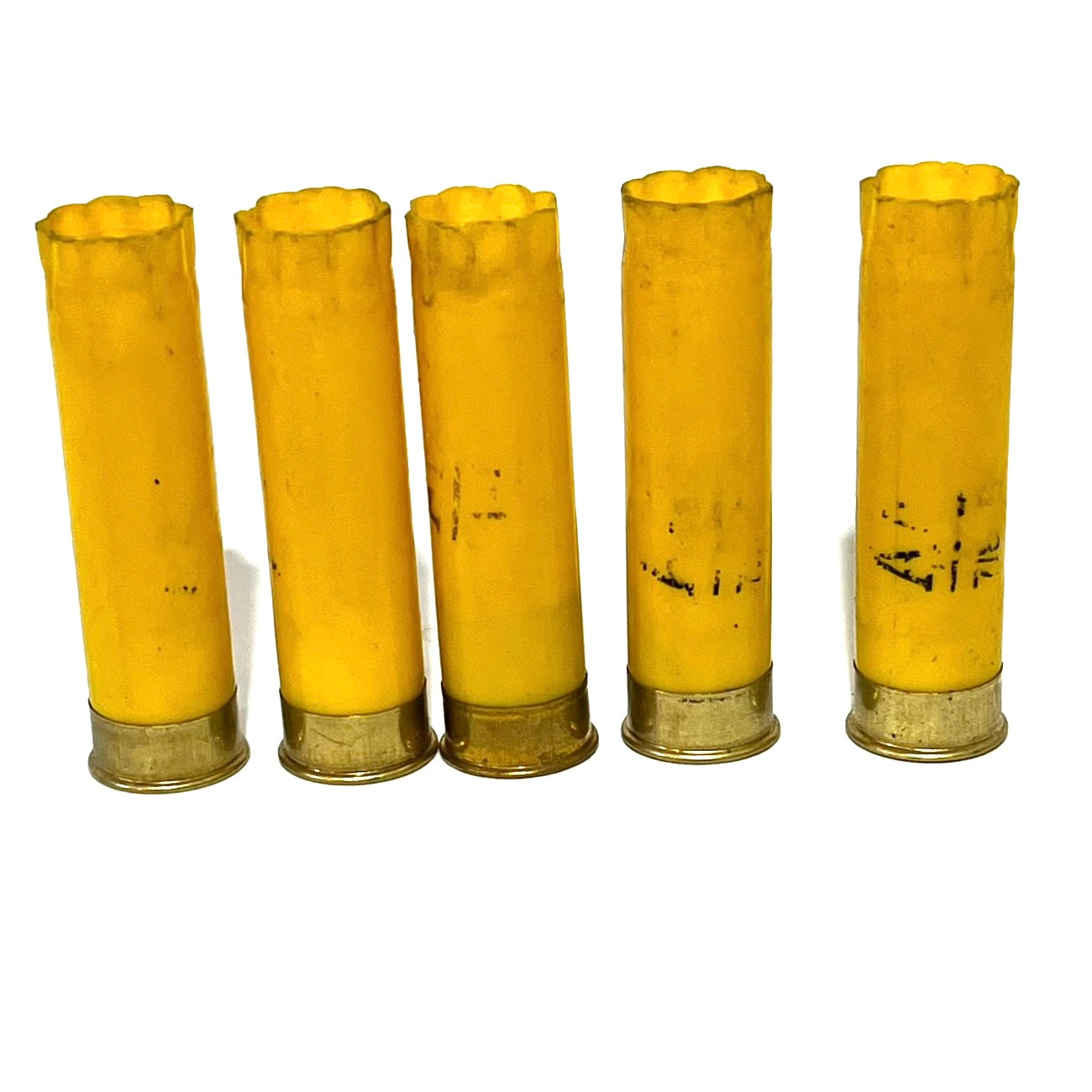 Five spent yellow shotshells stand in a row, their surfaces faded with faint smudge marks.