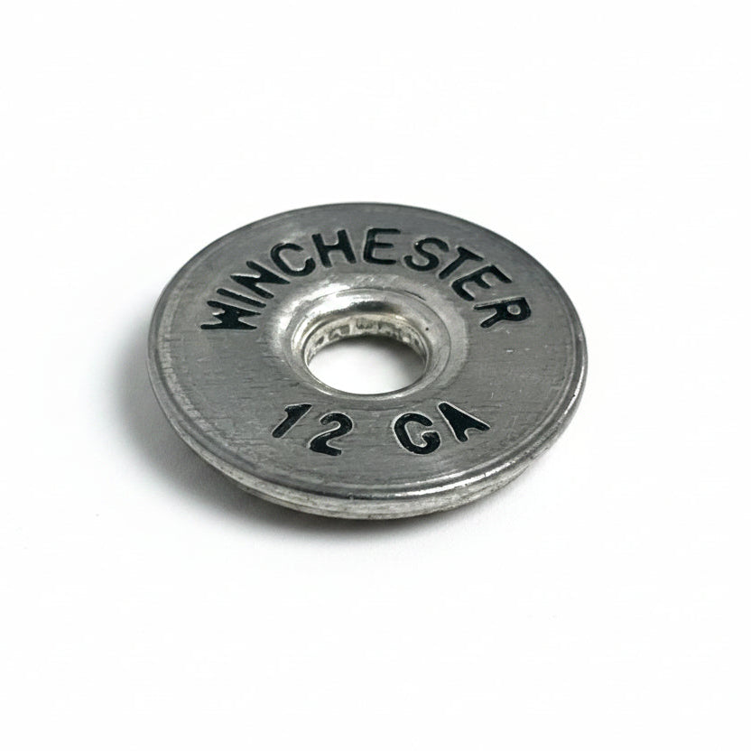 A close-up of a silver Winchester 12 gauge headstamp with black lettering on a white background.
