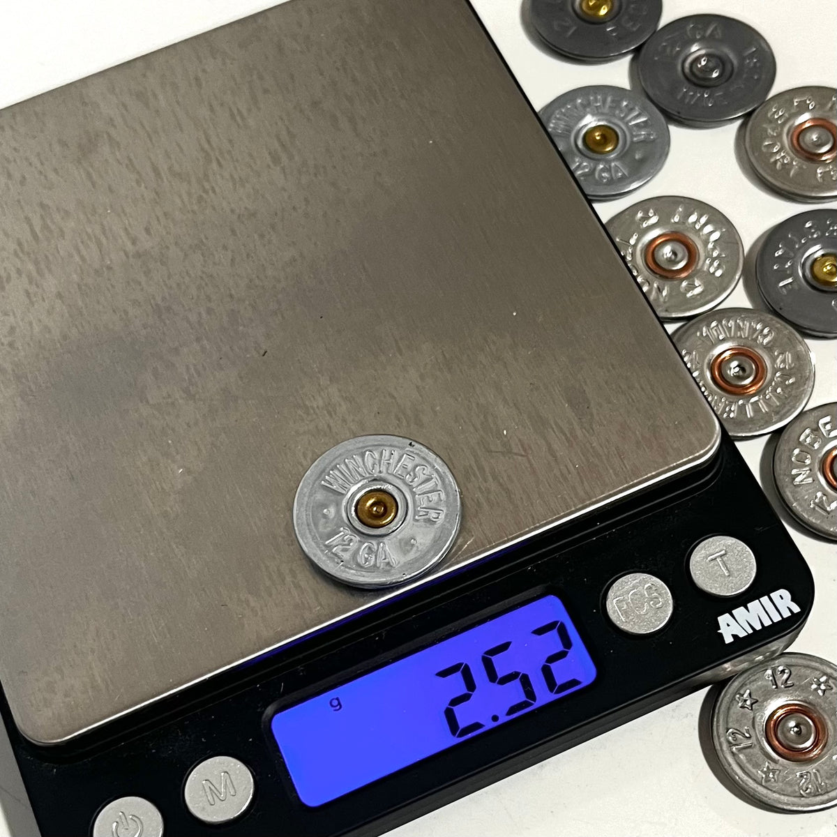 A silver Winchester 12 gauge shotgun shell slice on a digital scale reading 2.52 grams, with more slices beside it