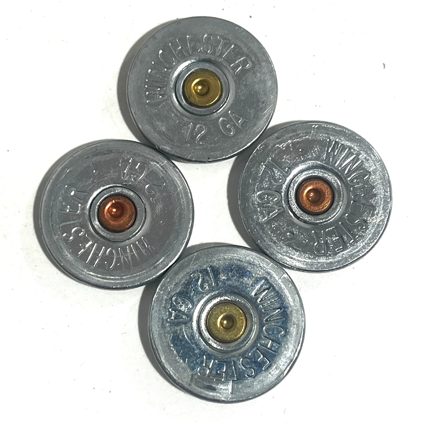 Four silver Winchester 12 gauge shotgun shell slices showing gold and copper primers