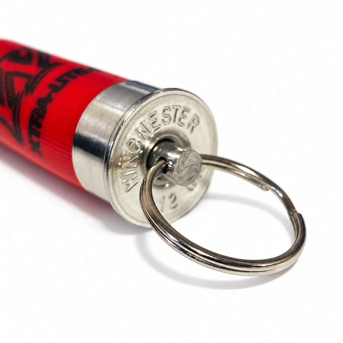 Close-up of the WINCHESTER 12 headstamp on a spent red hull keychain, with the steel pin and split ring