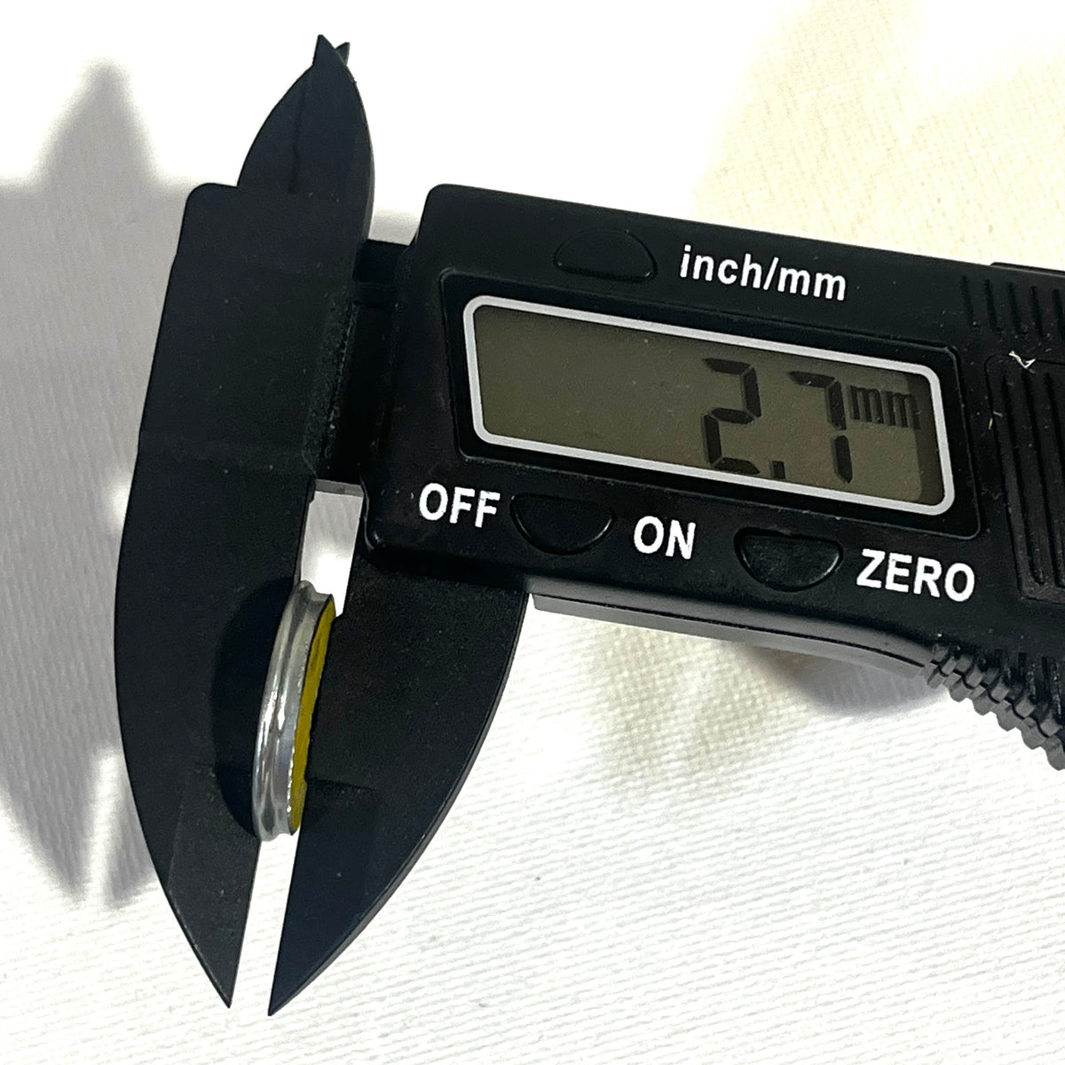 Digital caliper measuring the thickness of a shotgun shell slice at 2.7 millimeters