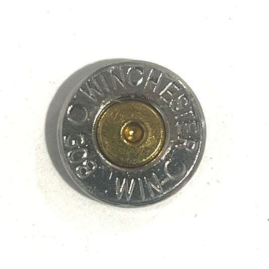 Close-up of a Winchester 308 nickel bullet slice with gold primer on a white background