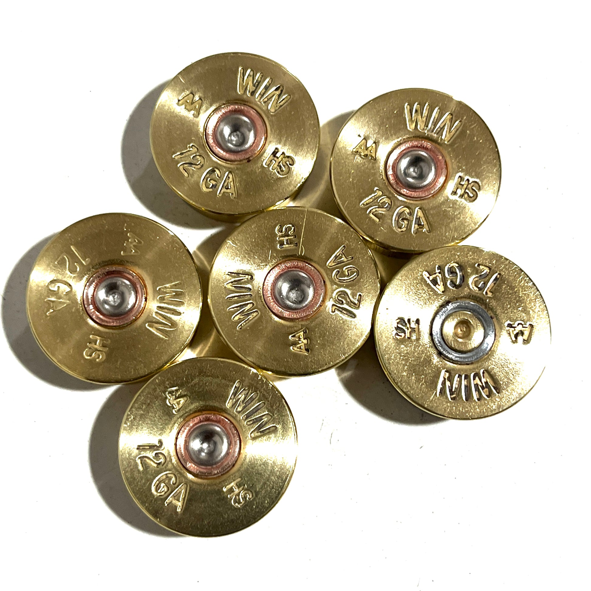 Seven gold Winchester AA 12 gauge shotgun shell headstamps arranged in a cluster, showing ‘WIN AA HS 12 GA’ stampings