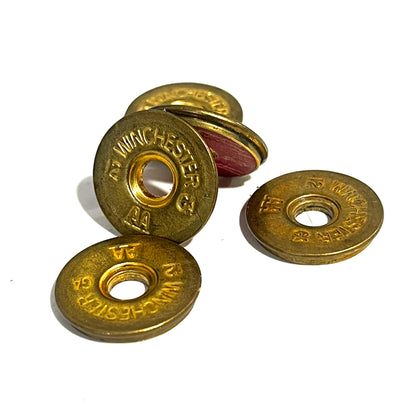 Four  Winchester AA shotgun shell slices rest together, their gold headstamps clearly stamped on each face.