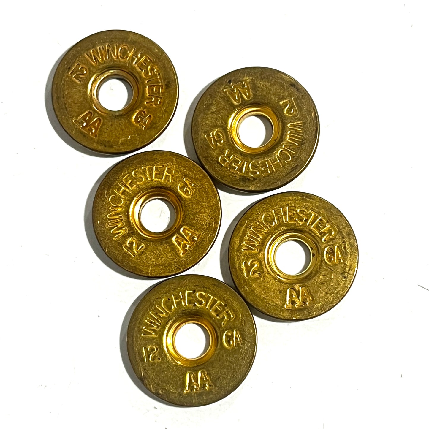 Five spent gold brass slices lie scattered together, each stamped with Winchester 12 GA AA markings.