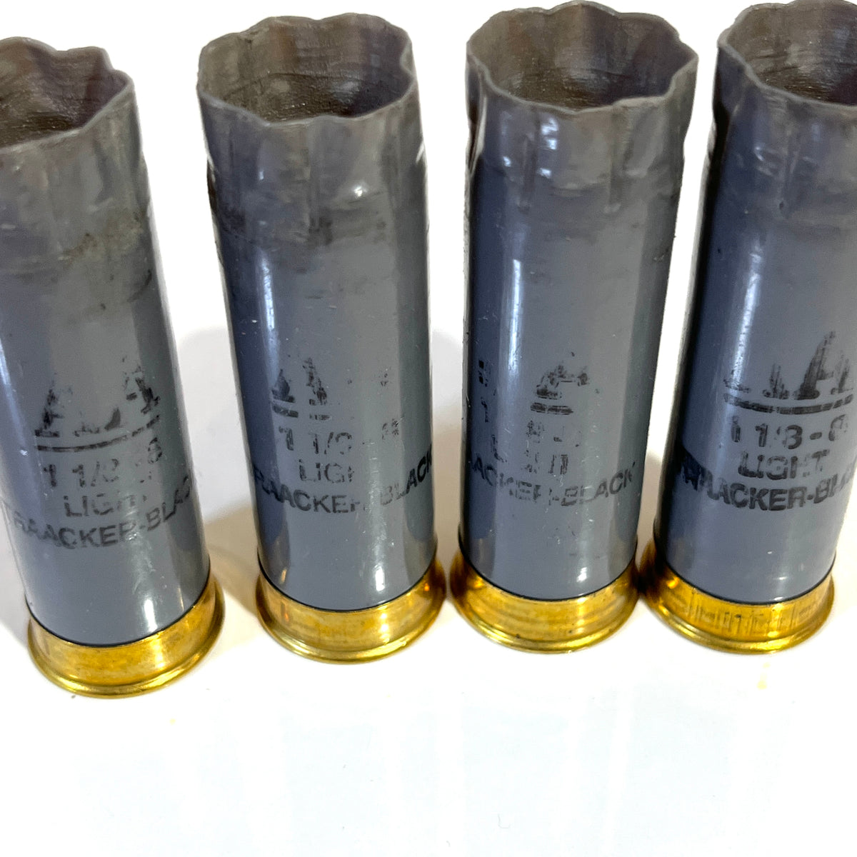 Four light gray Winchester AA 12 gauge shotgun shells with gold bases standing upright showing printed hull markings