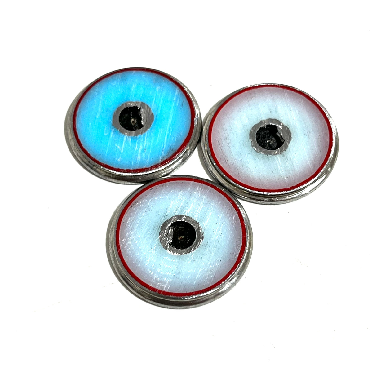 Three bullet slices viewed from the back, two white and one turquoise-blue, each with a red rim.