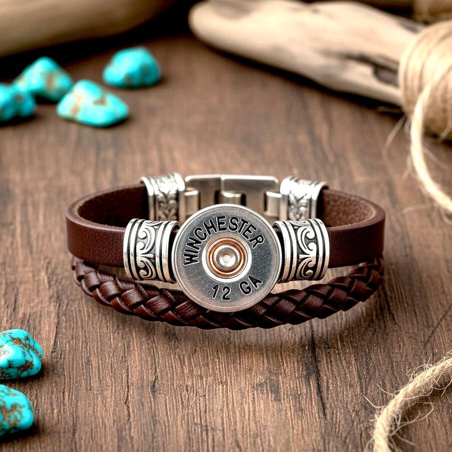 A Winchester 12 gauge shotgun shell slice hand painted set as a silver clasp on a braided leather bracelet with turquoise stones.