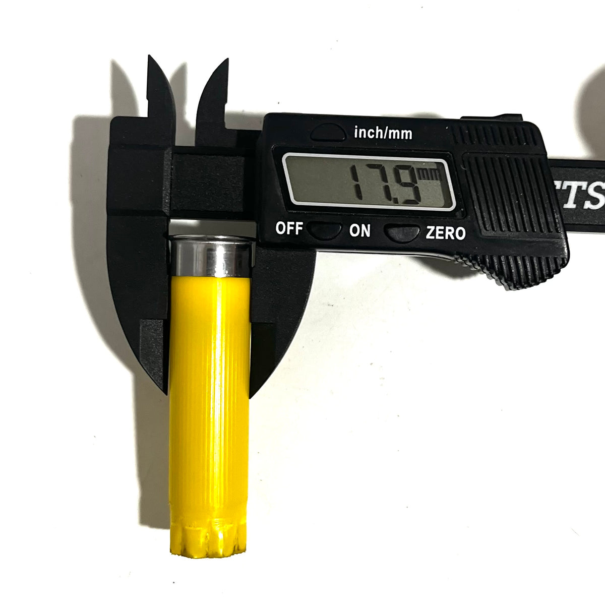 Digital caliper measuring the diameter of a yellow shotgun shell with silver base showing 17.9 mm
