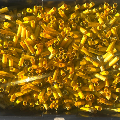 Overhead view of a large bin filled with mixed yellow shotgun shell hulls