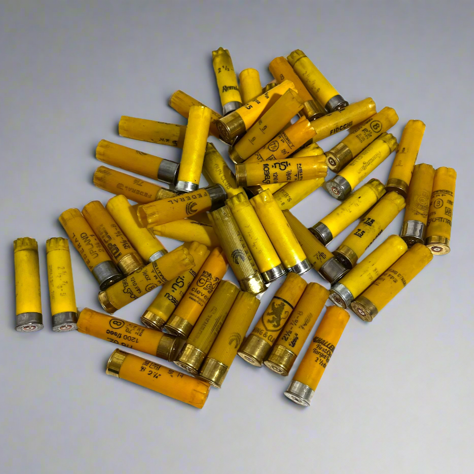 Large pile of mixed yellow shotgun shell hulls from various brands, viewed from above