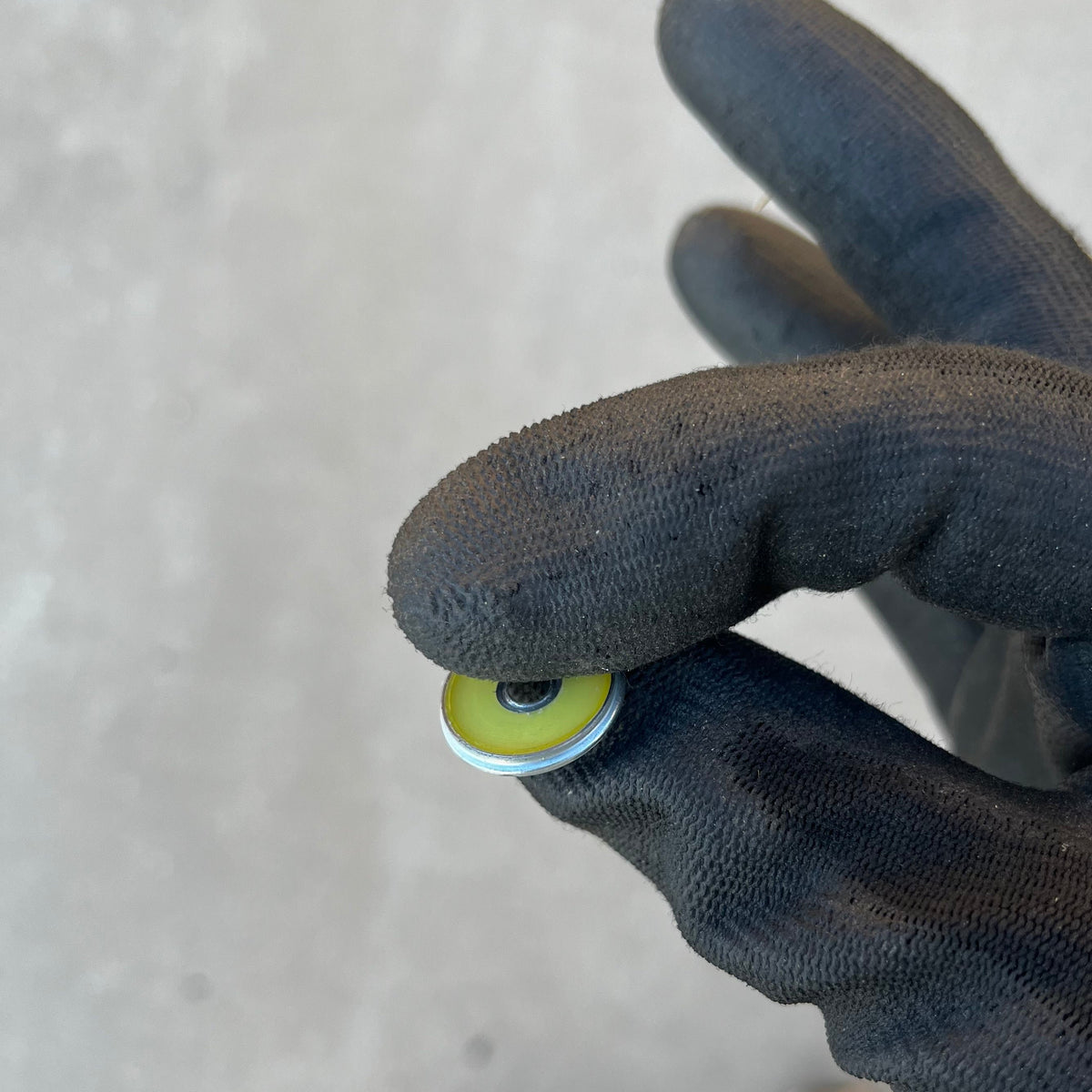 Yellow-painted Winchester 20 GA shotgun shell slice held between gloved fingers