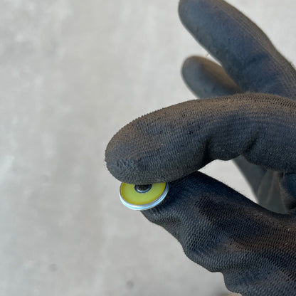 Yellow-painted Winchester 20 GA shotgun shell slice held between gloved fingers