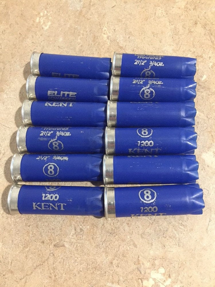 Two neat columns of navy blue Kent 12-gauge empty shotgun shells showing silver metal bases and open star crimps arranged on a light background.
