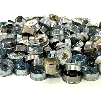 Silver 12 gauge shotgun shell bottoms heaped together, mixed finishes and manufacturer markings.