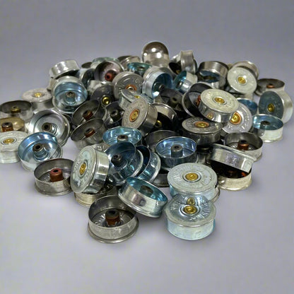 Silver 12 gauge shotgun shell end caps piled loosely together, showing mixed tarnish tones.