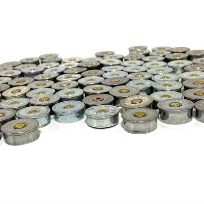 Silver 12 gauge shotgun shell headstamps standing upright in rows on white background.