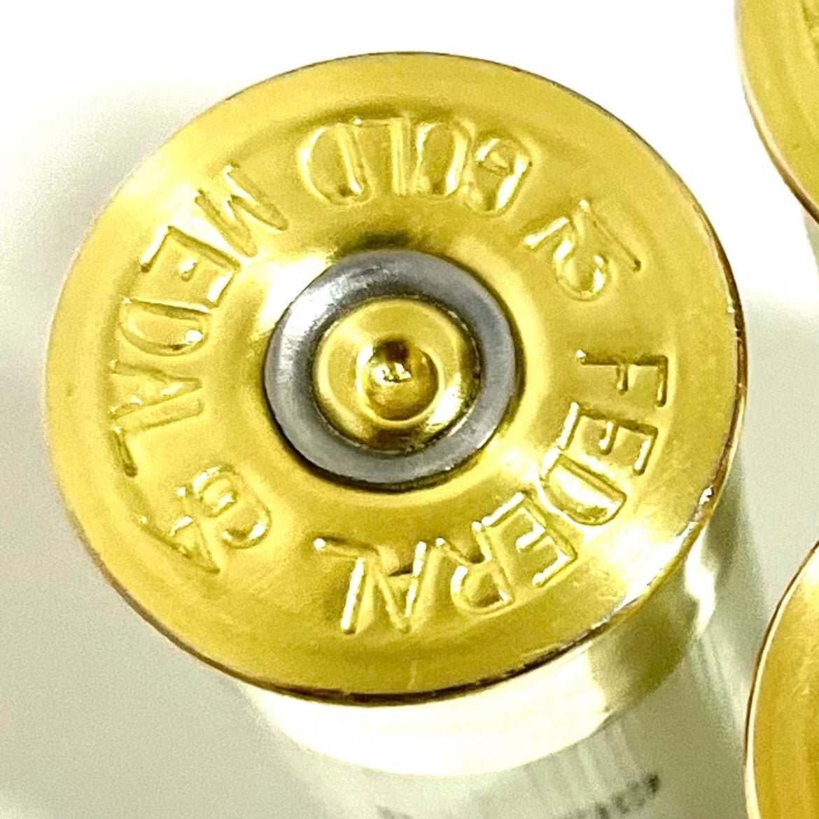 Close-up view of a gold brass bottom of a 12 gauge shotgun hull with Federal Gold Medal text engraved.