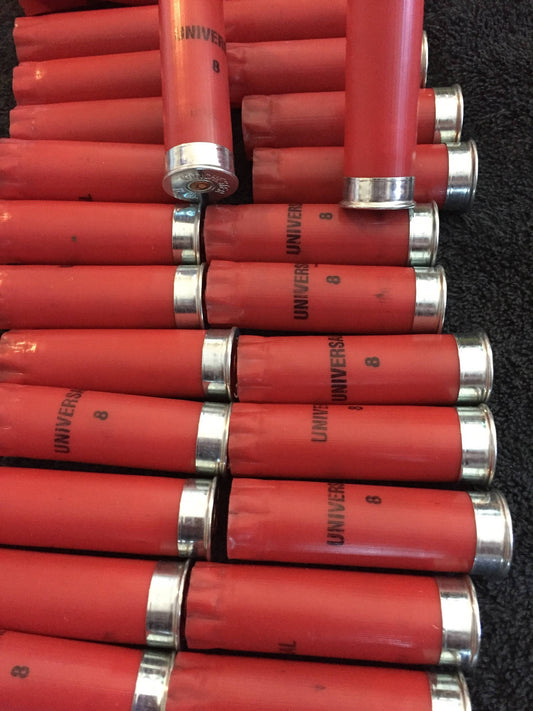 Red 12 gauge hulls with silver bases neatly stacked horizontally and vertically on a dark surface.