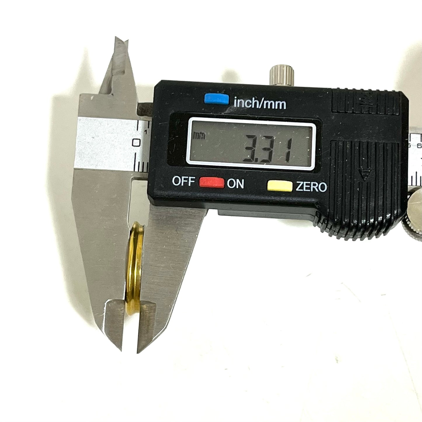 Digital caliper measuring the slice thickness of a 12 gauge shotgun shell headstamp slice showing 3.31 mm.