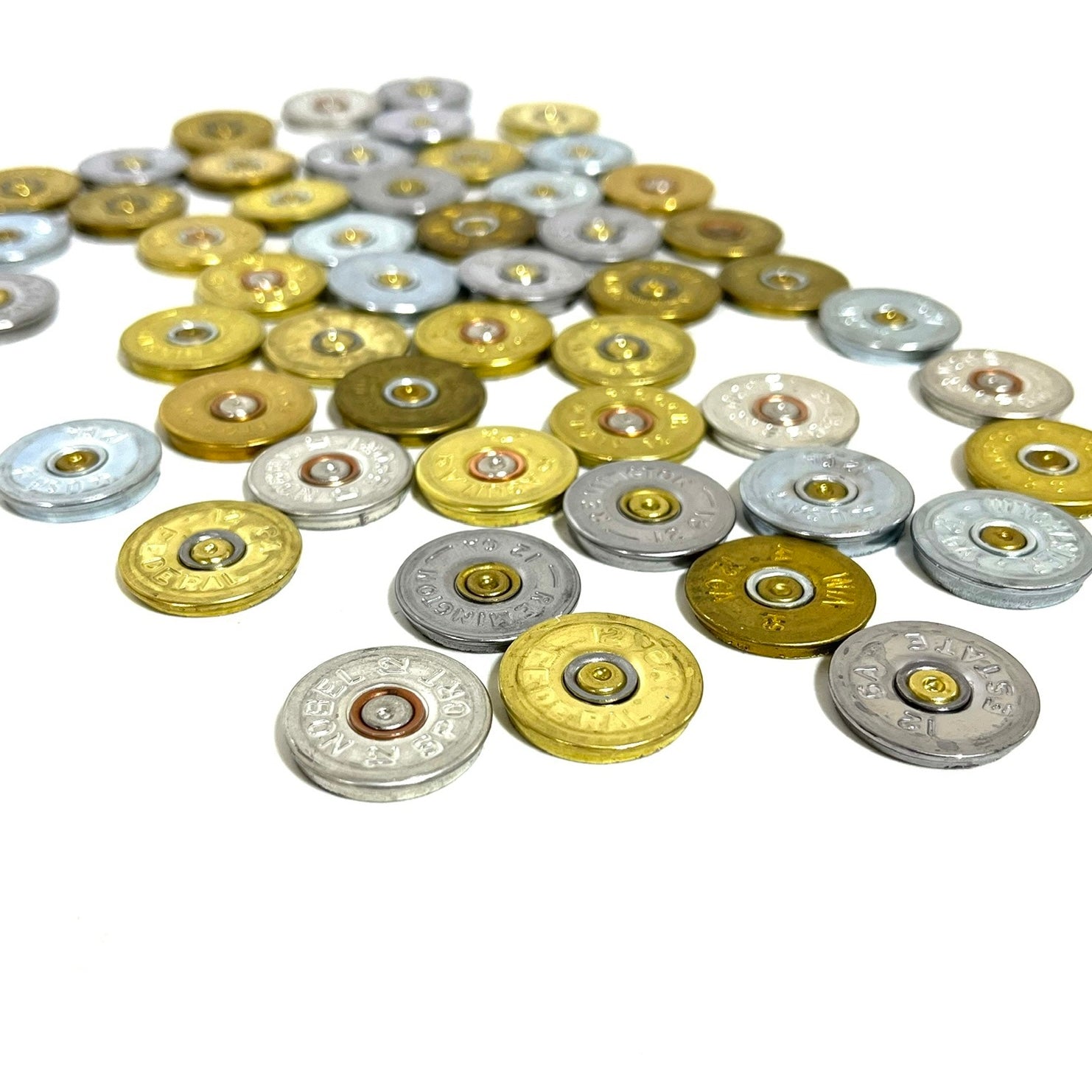 Scattered array of 12 gauge shotgun shell headstamp slices in mixed gold and silver on a white background.
