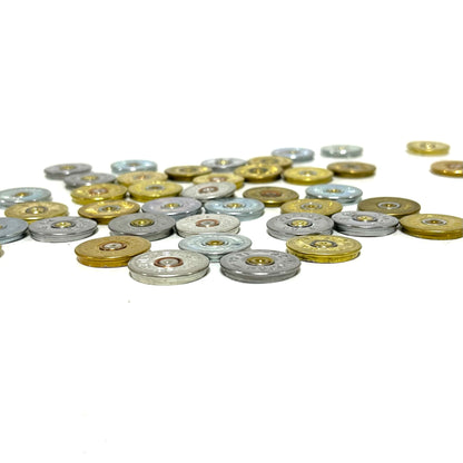 Low angle perspective of scattered gold and silver 12 gauge shotgun shell headstamp slices on a white background.