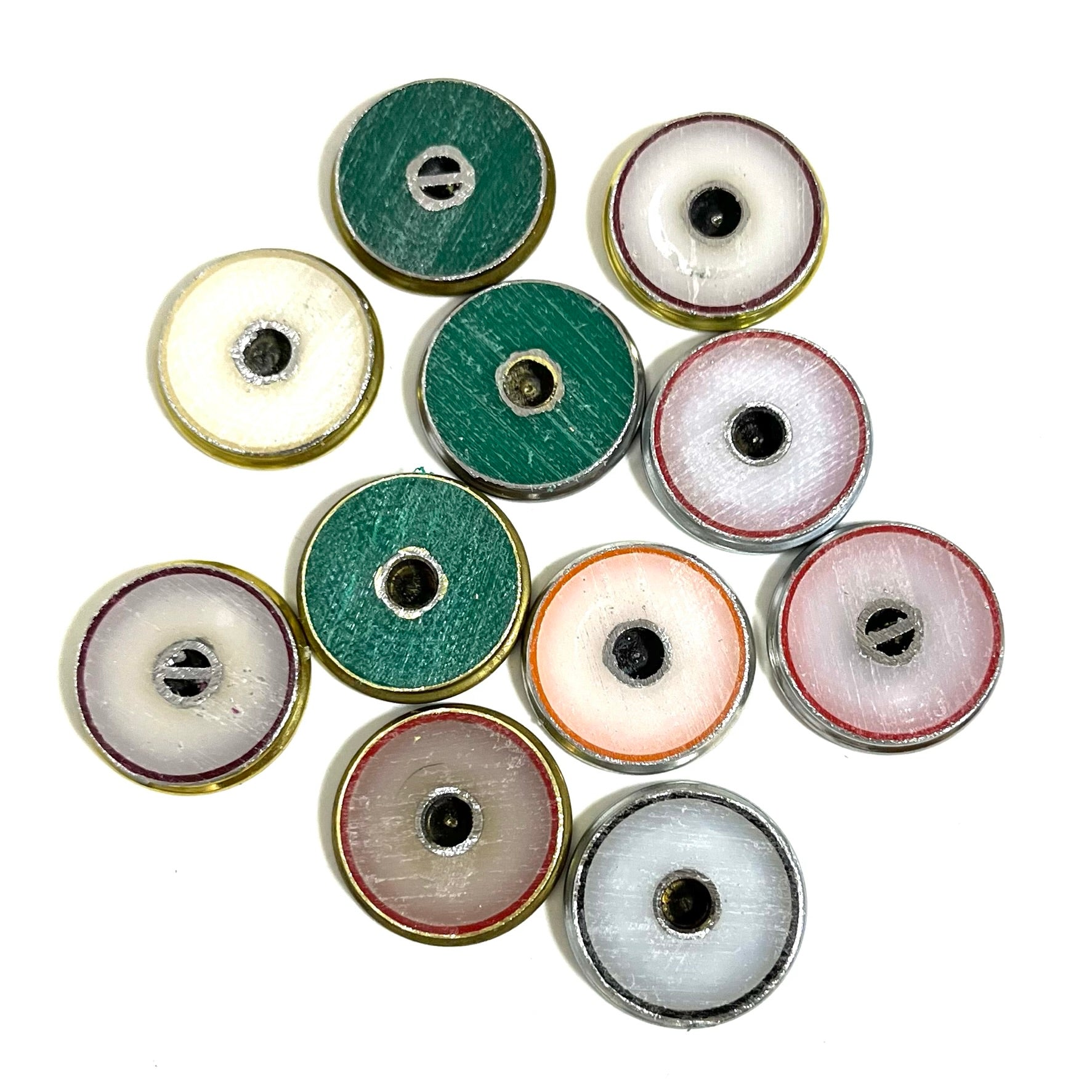 Eleven 12 gauge shotshell headstamp slices turned over showing colorful plastic base wads on a white background.