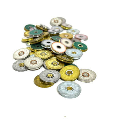 Stacked mound of mixed gold and silver 12 gauge shotgun shell headstamp slices on a white background.