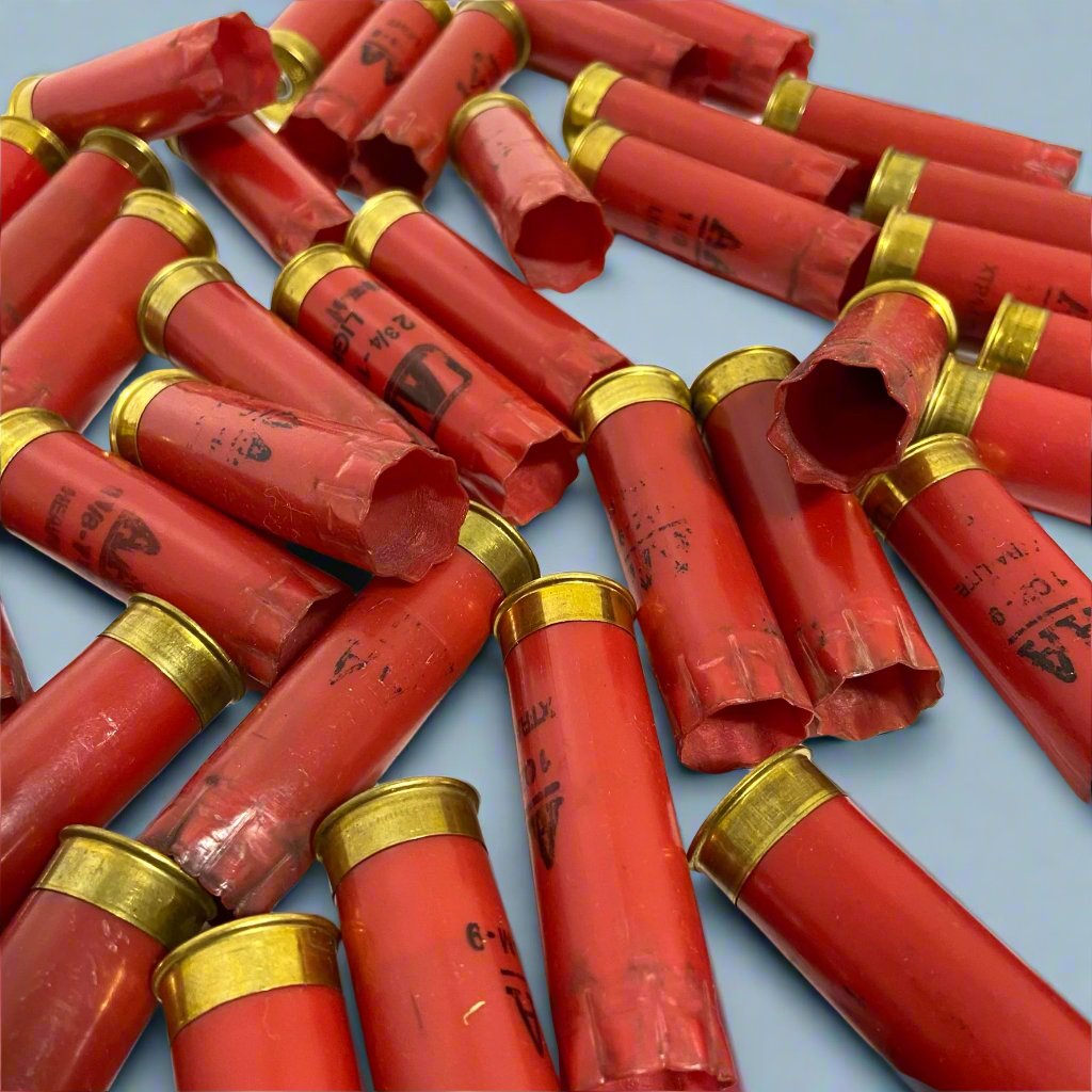 Red 12ga AA shotgun shell hulls crisscrossed at angles on a light blue surface, brass bases visible