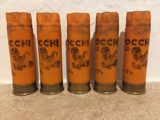 Five orange 12 gauge Fiocchi hulls with printed pheasant graphics standing in a row on a counter surface.