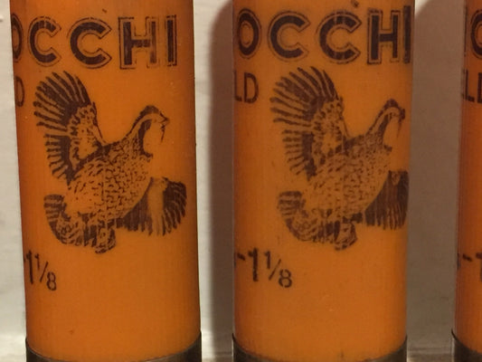 Macro close-up of orange 12 gauge shotshell casings showing black printed flying pheasant artwork and text.