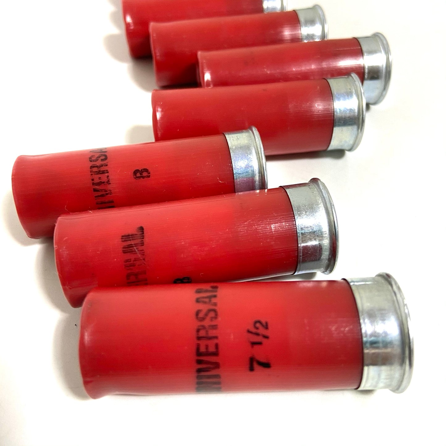Five red 12 gauge Winchester dummy rounds stacked horizontally on a white background with silver bases to the right.