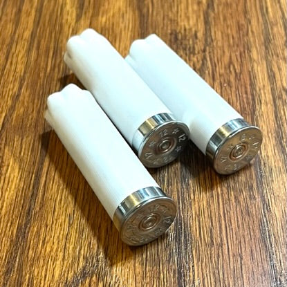 Three white empty shotgun casings crossed on a wood surface showing the brass primer ends
