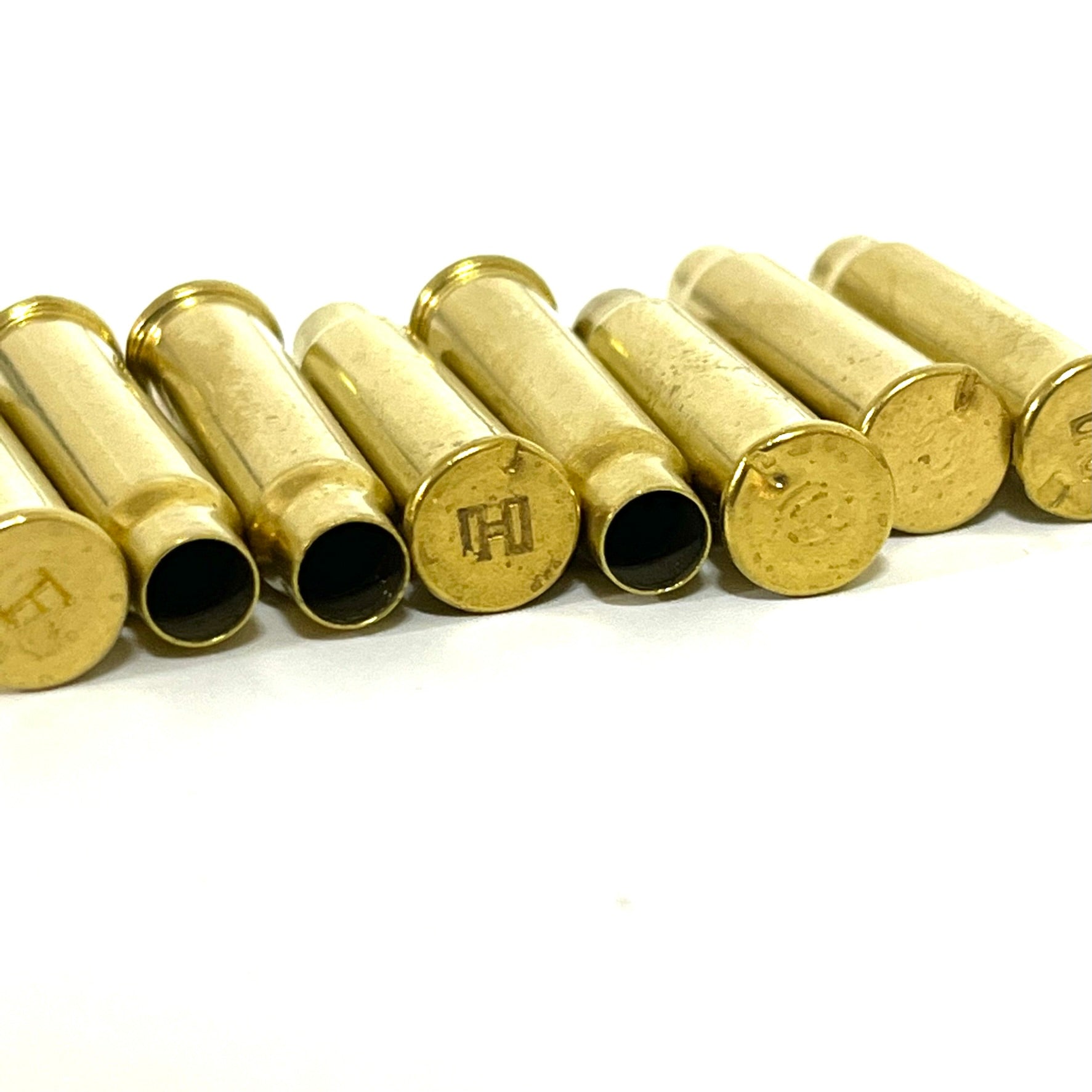 Six empty .17 HMR brass cartridge casings lined up in a row on a white background.