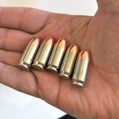 Five nickel snap caps with copper round nose bullets sitting in an open human hand.