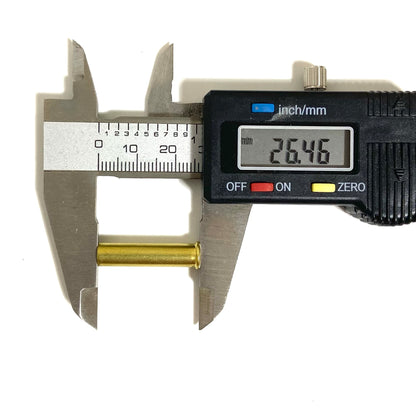 Stainless steel digital caliper measuring overall length of a .22 WMR brass shell showing 26.46 mm on display.
