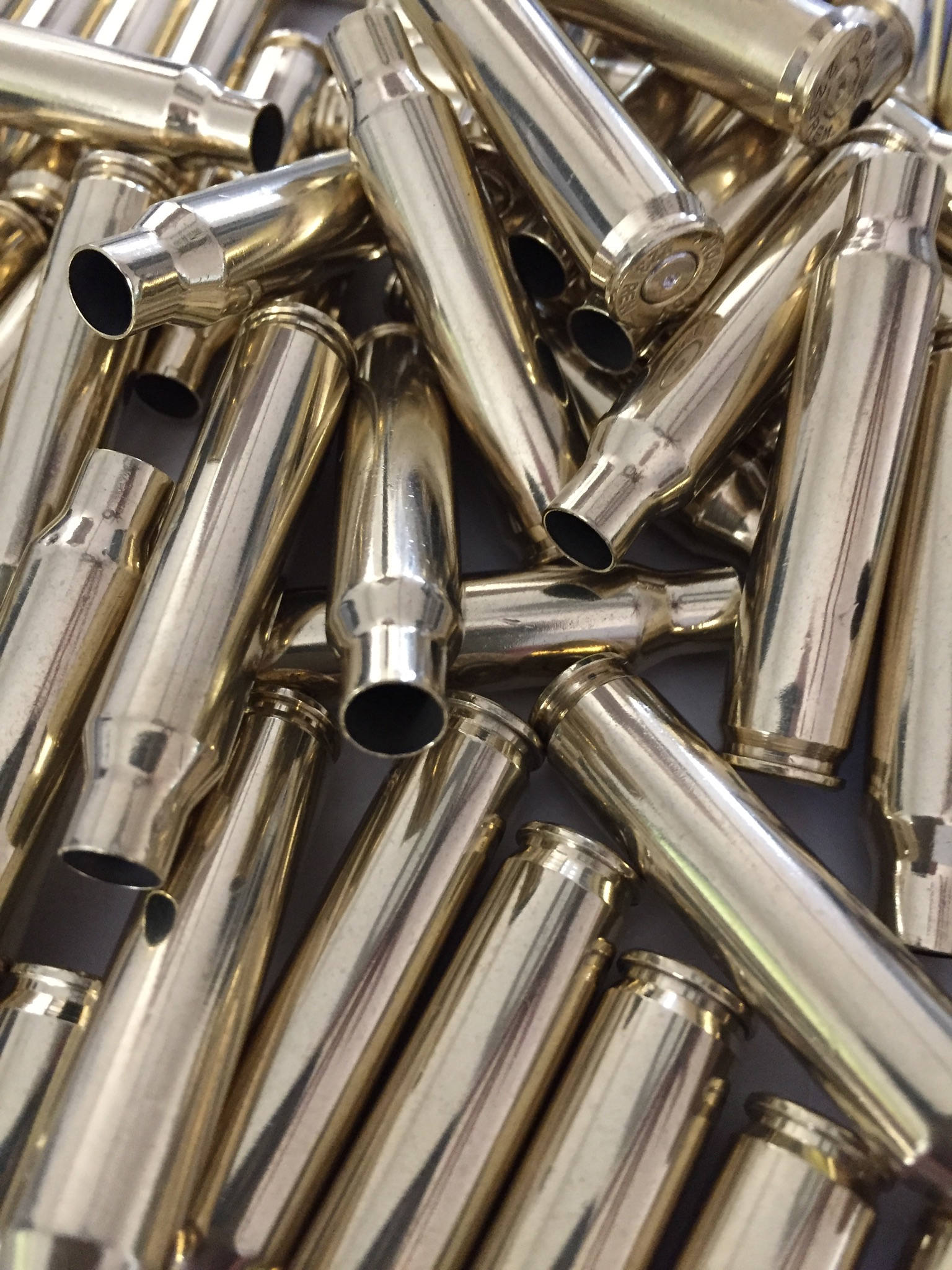 Polished brass 223 5.56 empty spent bullet casings lying at angles on a dark surface