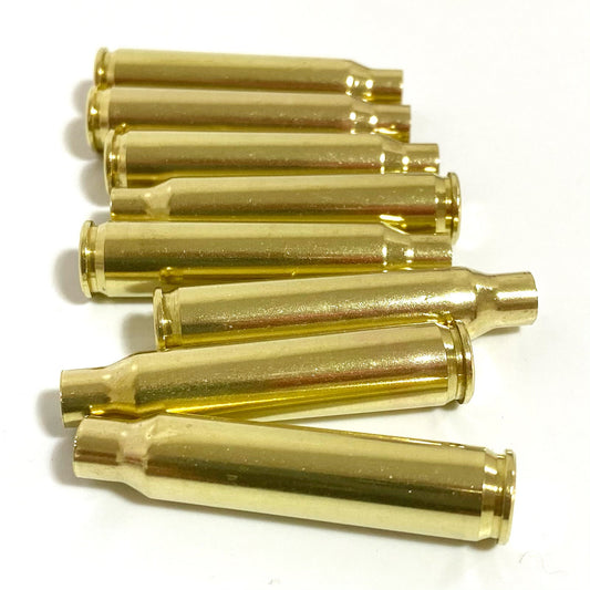 Seven polished brass 223 casings lying horizontally in a staggered stack against a plain white background.