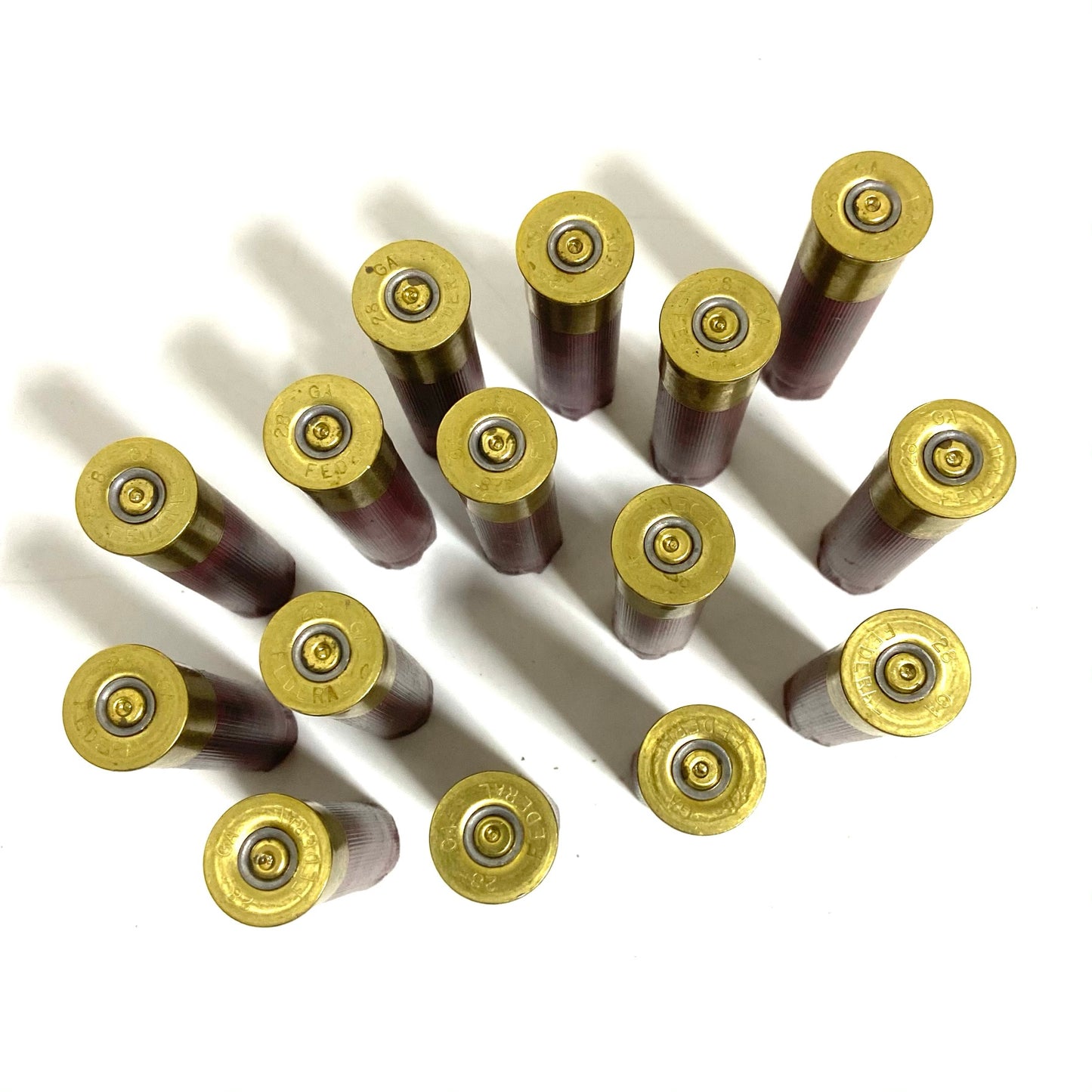 Fifteen 28 gauge dark red shells laid base-up in a diagonal grid, showing brass heads with spent primers