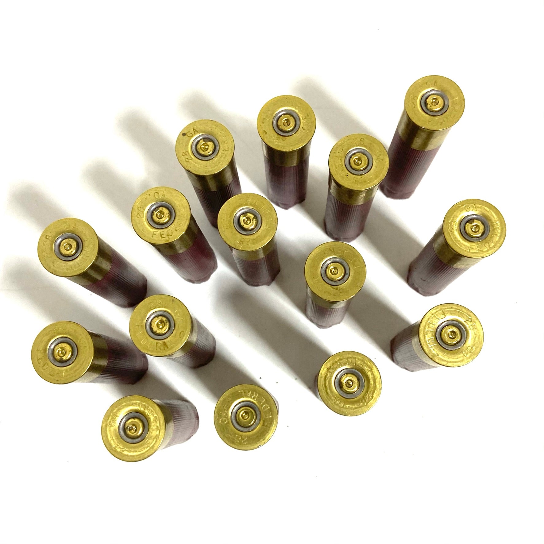 Fifteen 28 gauge dark red shells laid base-up in a diagonal grid, showing brass heads with spent primers