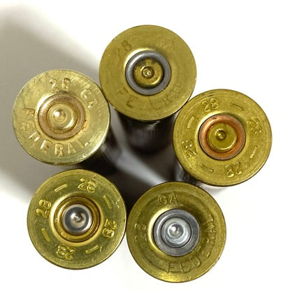 Five 28 gauge brass hull bases in a pinwheel pattern, showing 28 GA and Federal headstamp markings and mixed primer colors