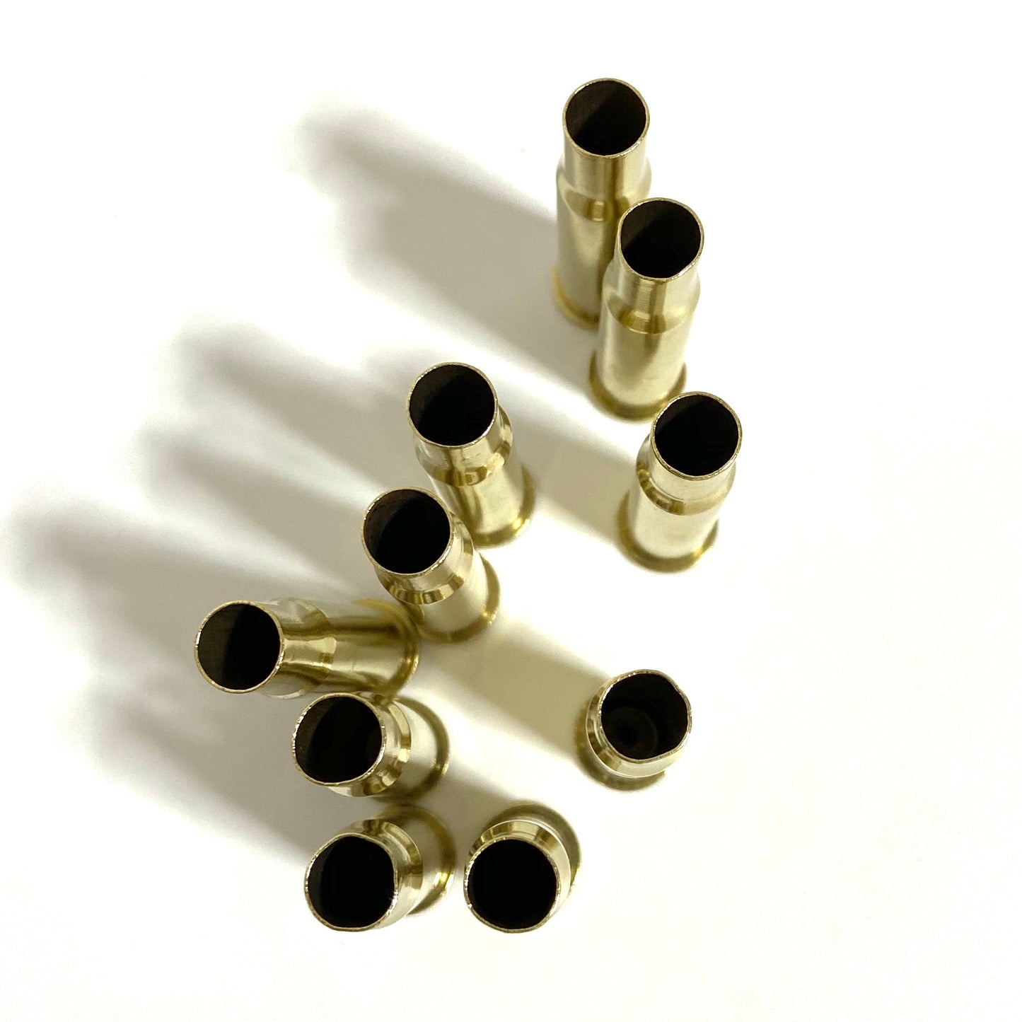 Top view of polished 30-30 brass casing necks, standing upright, showing tumbled gold finish and open mouths.
