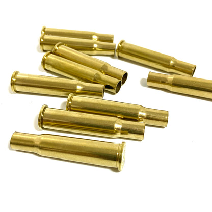 Group of polished 30-30 Winchester brass casings scattered on white, bright gold shine, genuine empty shells.
