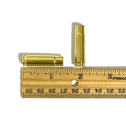 A 300 AAC Blackout brass rifle casing placed next to a ruler showing its physical size and dimensions.